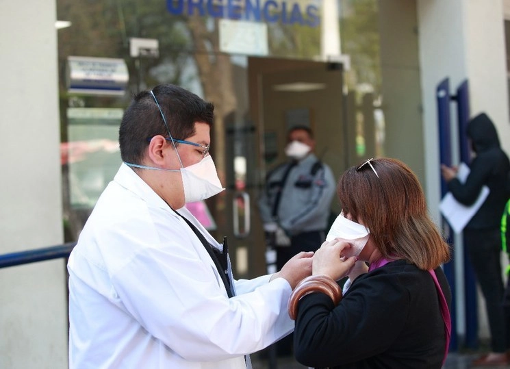 Un médico entrega cubrebocas a familiares de pacientes del Instituto Nacional de Enfermedades Respiratorias. Foto Alfredo Domínguez
