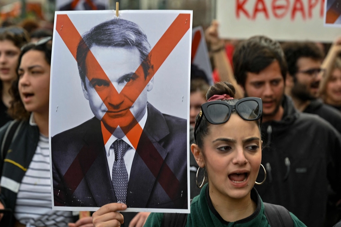 Una mujer sostiene una fotografía del primer ministro griego, Kyriakos Mitsotakis, tachada con una cruz roja durante una manifestación por la peor tragedia ferroviaria del país que mató a 57 personas el 28 de febrero. Foto Afp / Archivo