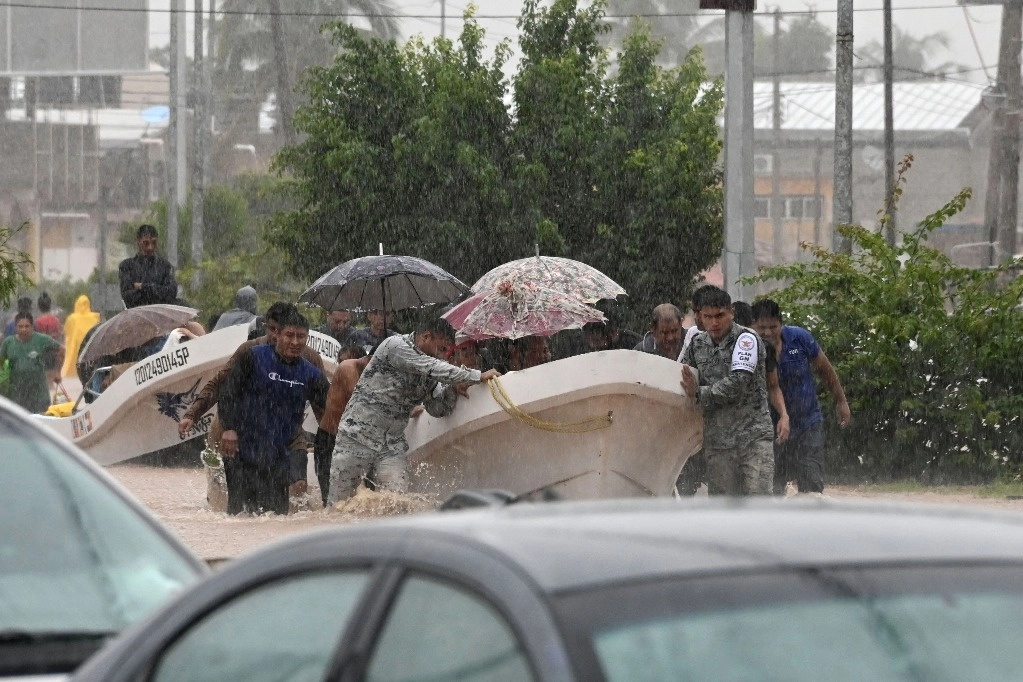 Miembros de la Guardia Nacional y oficiales de policía ayudan a personas en una calle inundada tras el paso del huracán John en Acapulco, México, el 26 de septiembre de 2024. Foto Afp