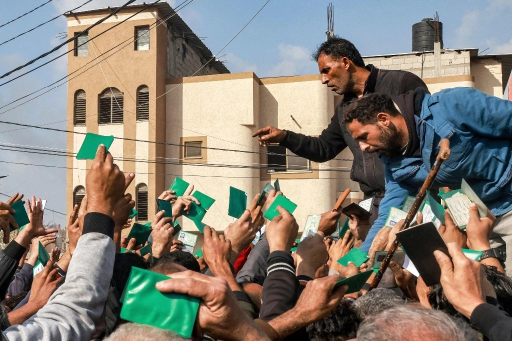 Palestinos muestran sus tarjetas de identidad para recibir raciones de alimentos en Rafah, al sur de la Franja de Gaza. Foto Afp