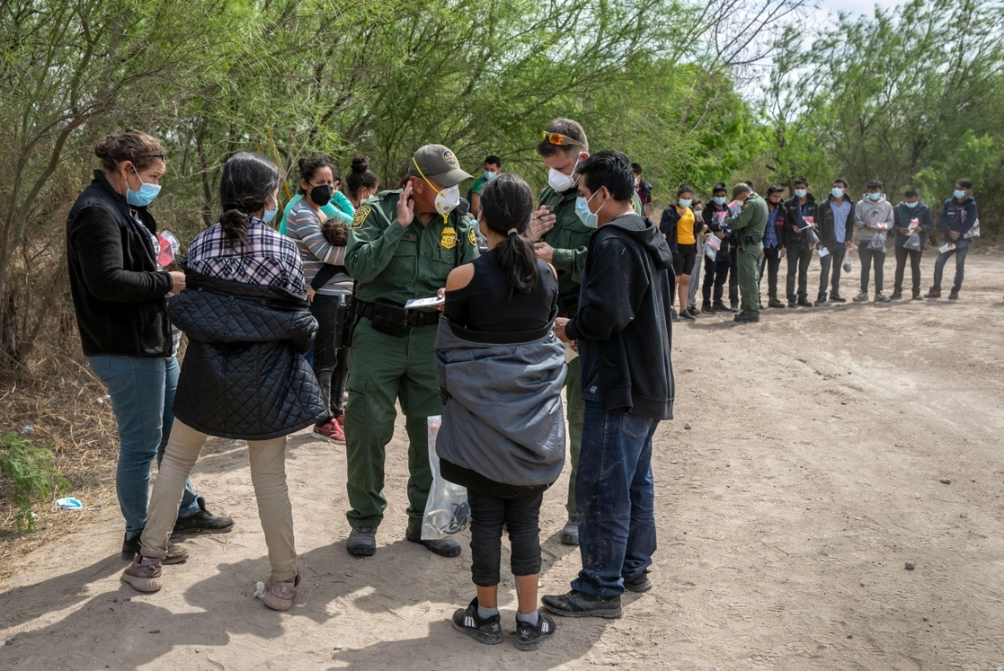 En Hidalgo, Texas, agentes de la Patrulla Fronteriza interrogan a varias familias que acaban de cruzar el río Bravo, el 25 de marzo de 2021. En primer plano, varios menores no acompañados, que serán transportados a instalaciones para migrantes, de acuerdo con la política de no expulsarlos. Foto Afp