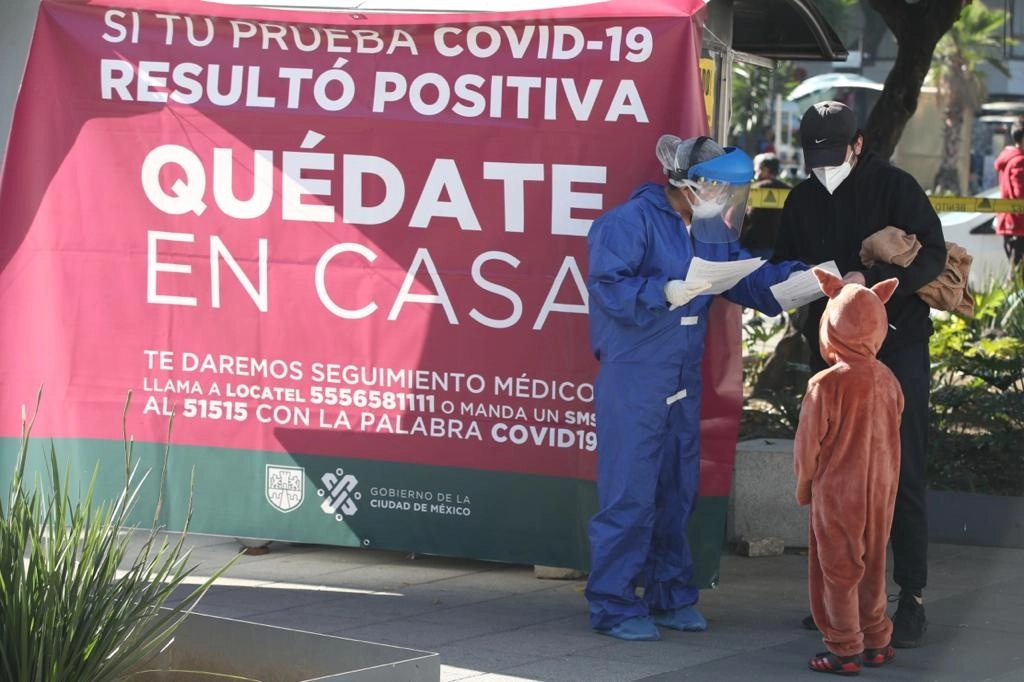Padre e hijo reciben sus resultados de pruebas de detección de Covid-19 en un quiosco de salud, en la Ciudad de México. Foto José Antonio López