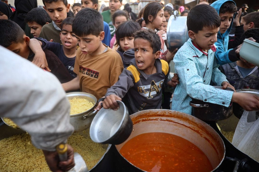Niños palestinos claman por comida en un punto de distribución en Nuseirat, Gaza. Foto