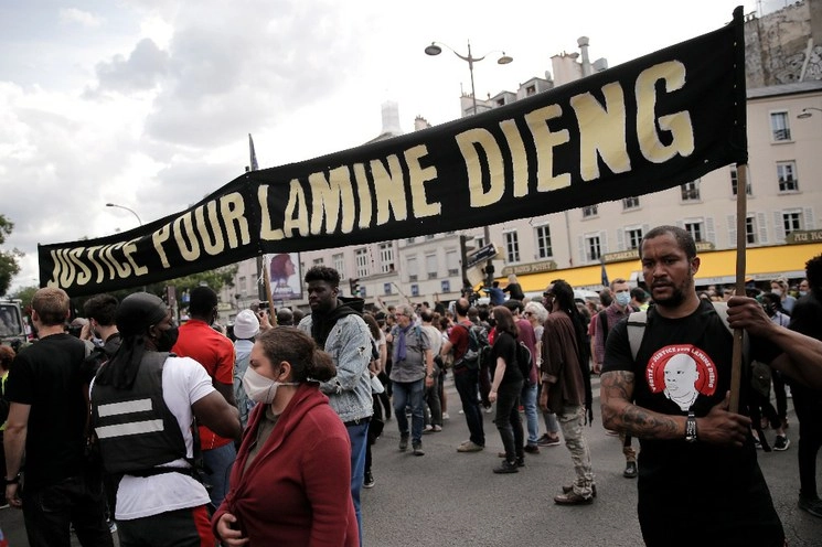 La gente marcha sosteniendo una pancarta durante una protesta en memoria de Lamine Dieng, un franco-senegalés de 25 años que murió en una camioneta de la policía después de ser arrestado en 2007, en París, el sábado 20 de junio de 2020. Foto Ap
