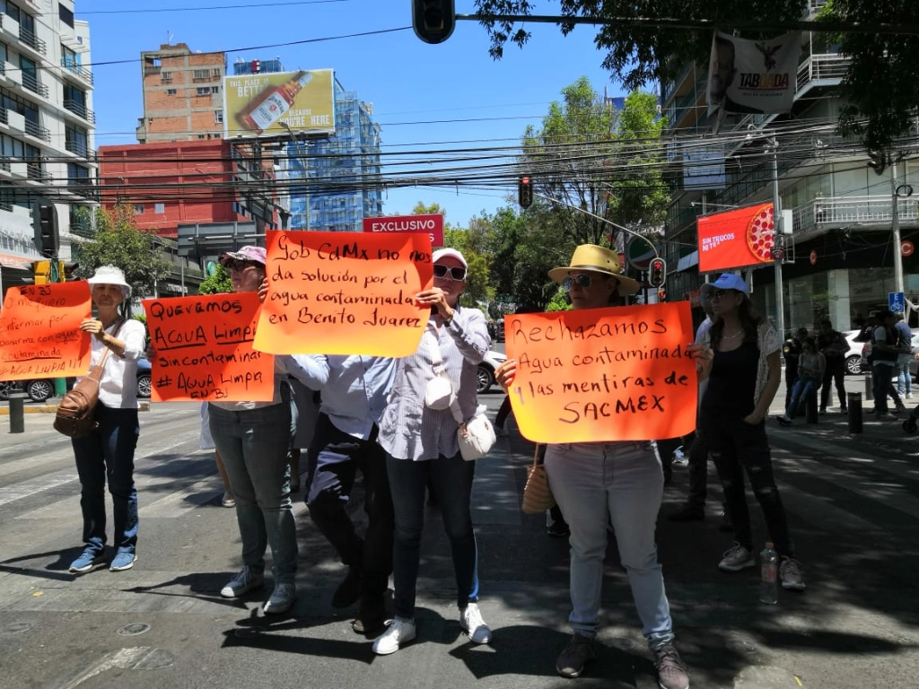 Los manifestantes levantan cartulinas de color naranja fluorescente en las que se leen las leyendas "queremos agua limpia, sin contaminar, #agua limpia  en  Benito Juárez". Foto Elba Mónica Bravo 