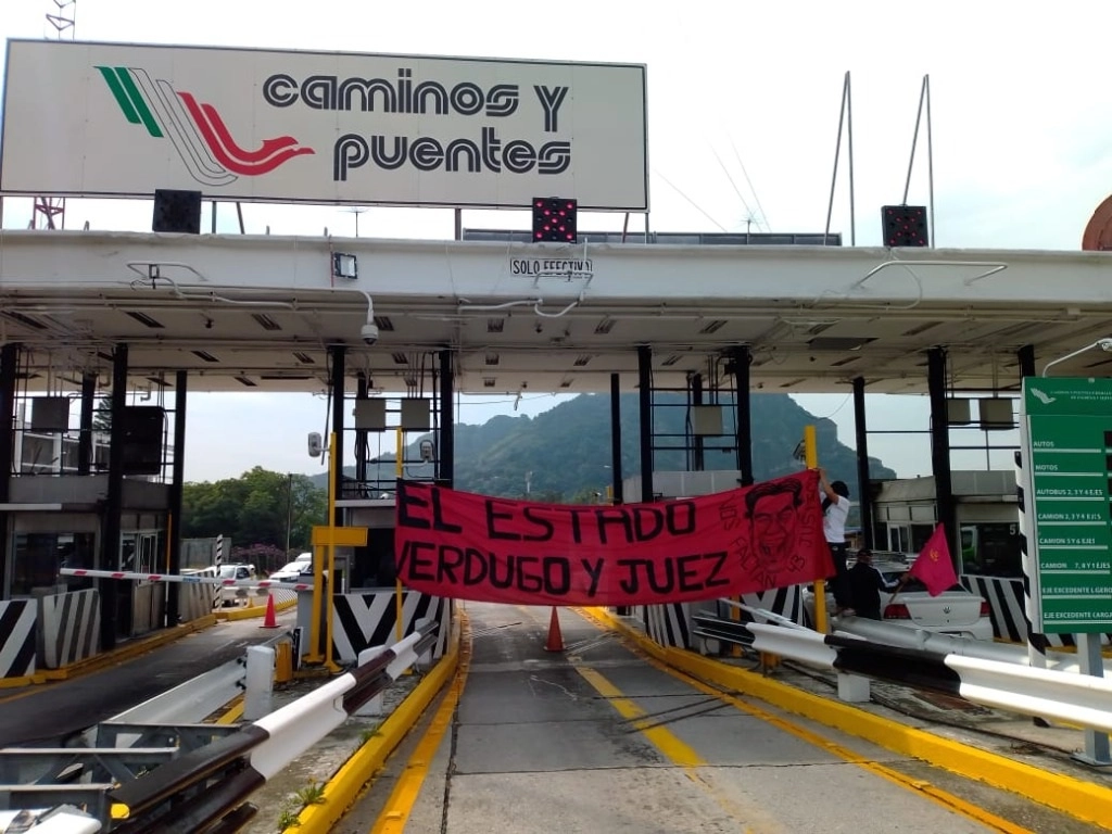 Durante la protesta colocaron una manta color rojo con letras negras que decía: “El estado verdugo y juez”, mientras gritaban:“¡Ayotzi somos todos, Ayotzi somos todos!. Foto Rubicela Morelos
