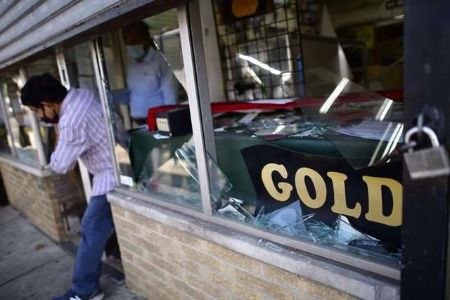 El dueño de un comercio limpian los destrozos después de las protestas de anoche contra la muerte de George Floyd, en Filadelfia, EU. Foto Afp 