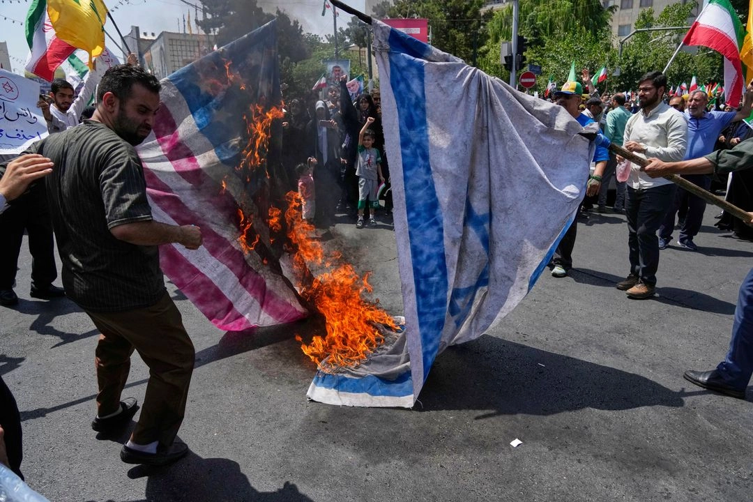 Manifestantes iraníes queman las banderas de Israel y Estados Unidos durante una protesta para condenar los ataques israelíes en varias ciudades de Irán, después de la ceremonia de oraciones en Teherán, Irán, el  20 de junio de 2025.