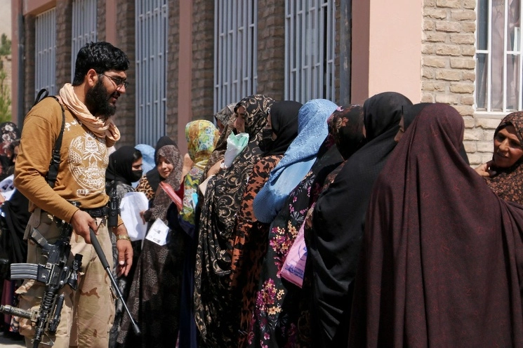 Un talibán controla una fila mujeres afganas que se encuentra frente a la oficina de pasaportes en Herat, Afganistán, el 26 de agosto de 2023. Foto Afp