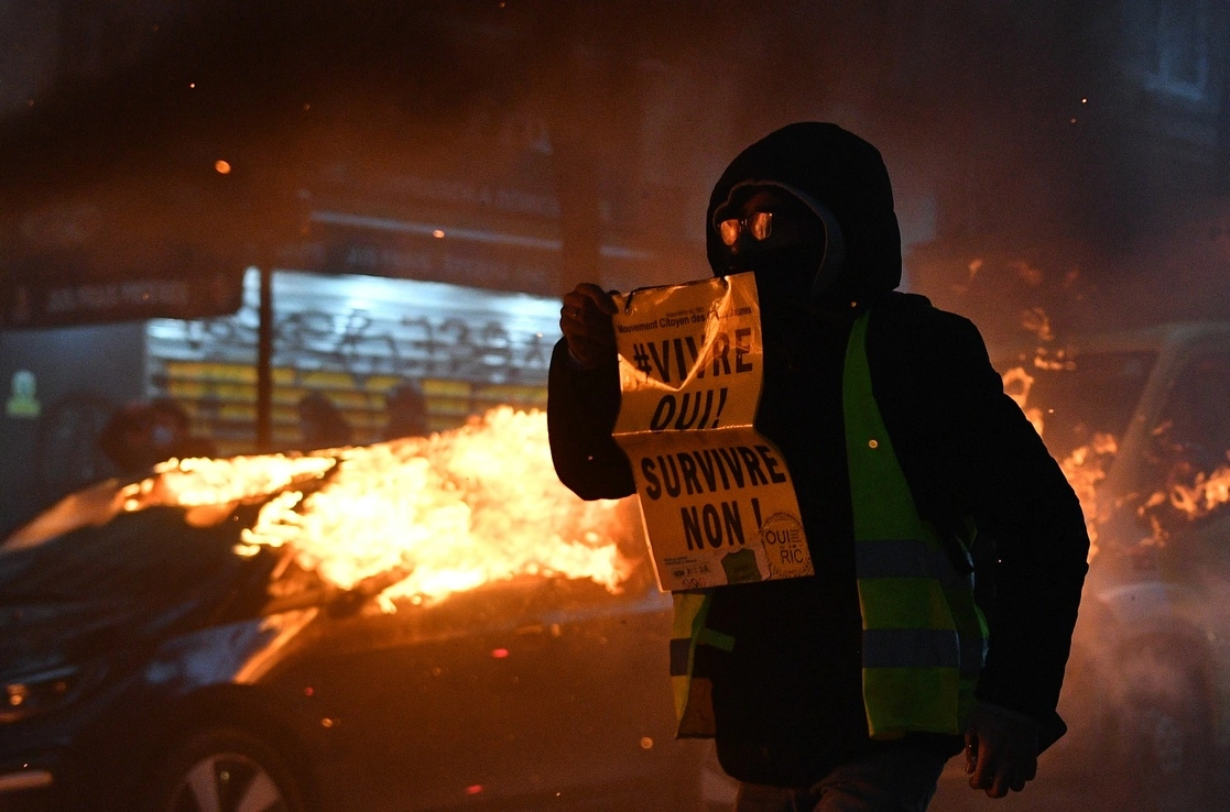 Un manifestante antigubernamental de los "chalecos amarillos" sostiene un cartel que dice "¡Viviendo, sí! Sobrevivir, ¡no! durante una manifestación por los 'derechos sociales' y contra el proyecto de ley de 'seguridad global' en París, Francia. Foto  Afp