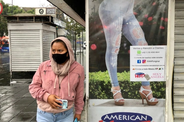 Una mujer junto a un cartel publicitario en la CDMX. Foto Luis Castillo