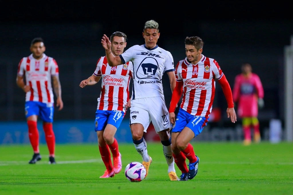 Jugadores de Chivas atajan a Favio Álvarez de Pumas quien domina el esférico. Foto Jam Media