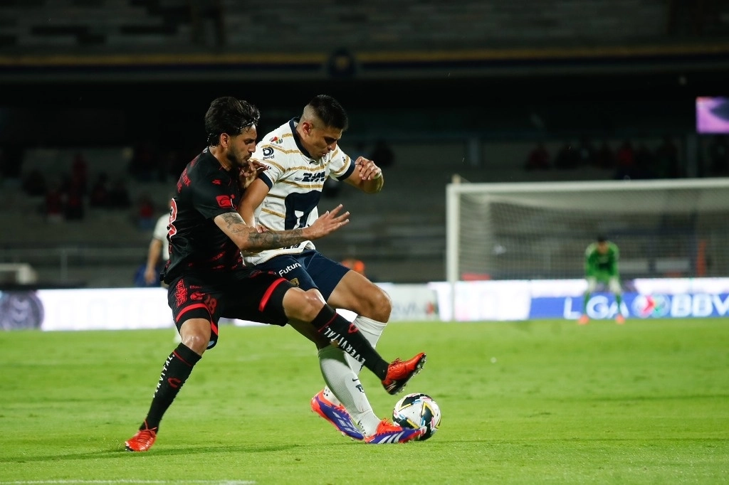 El delantero Guillermo Martínez, de Pumas, disputa el balón al defensa Jesús Gómez, de los Xolos. Foto Cristina Rodríguez 