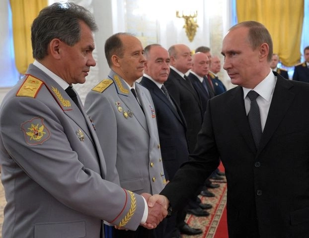 Vladimir Putin le da la mano al ministro de Defensa, Sergei Shoigu, mientras se reúne con los altos oficiales recién ascendidos. Foto Afp