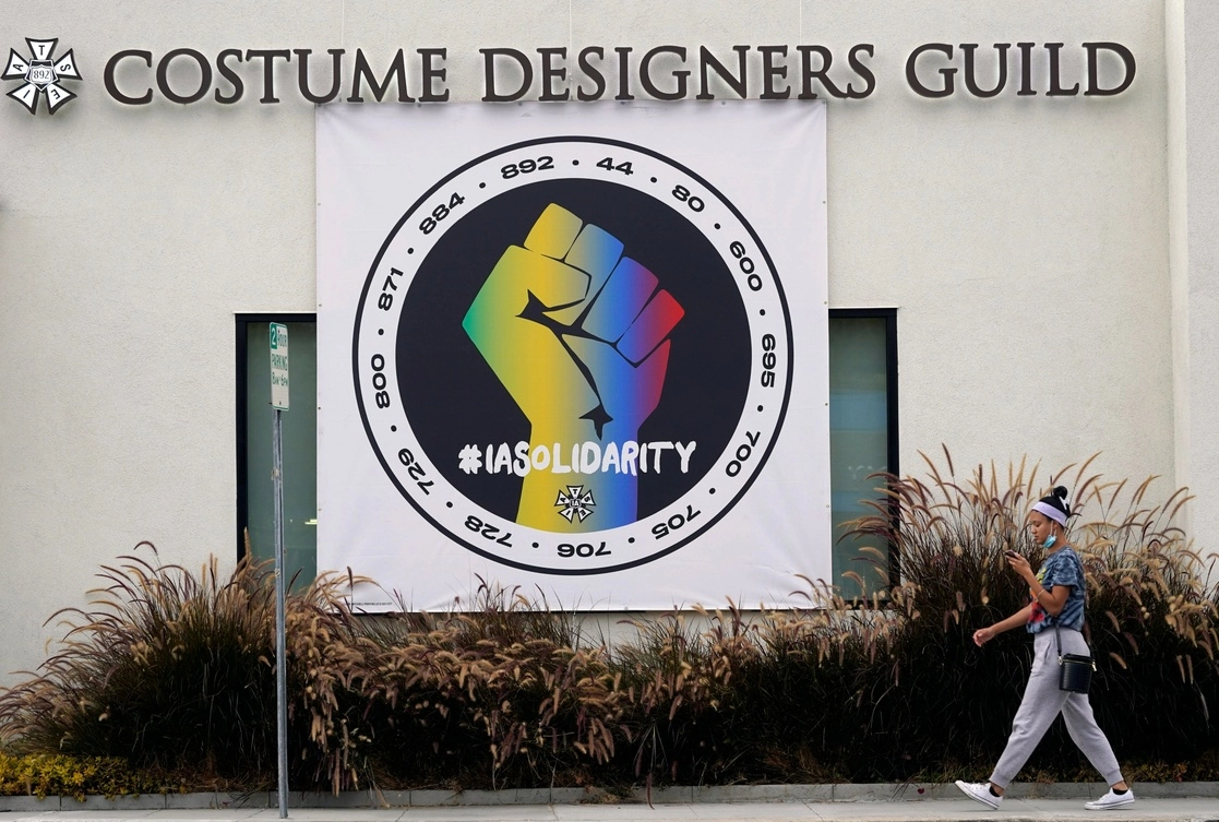 Una transeúnte pasa junto a un cartel que defiende la solidaridad sindical frente a un edificio de oficinas del Gremio de Diseñadores de Vestuario, en Burbank, California, el 4 de octubre de 2021. El IATSE votó para autorizar una huelga por primera vez en sus 128 años de historia. Foto Ap