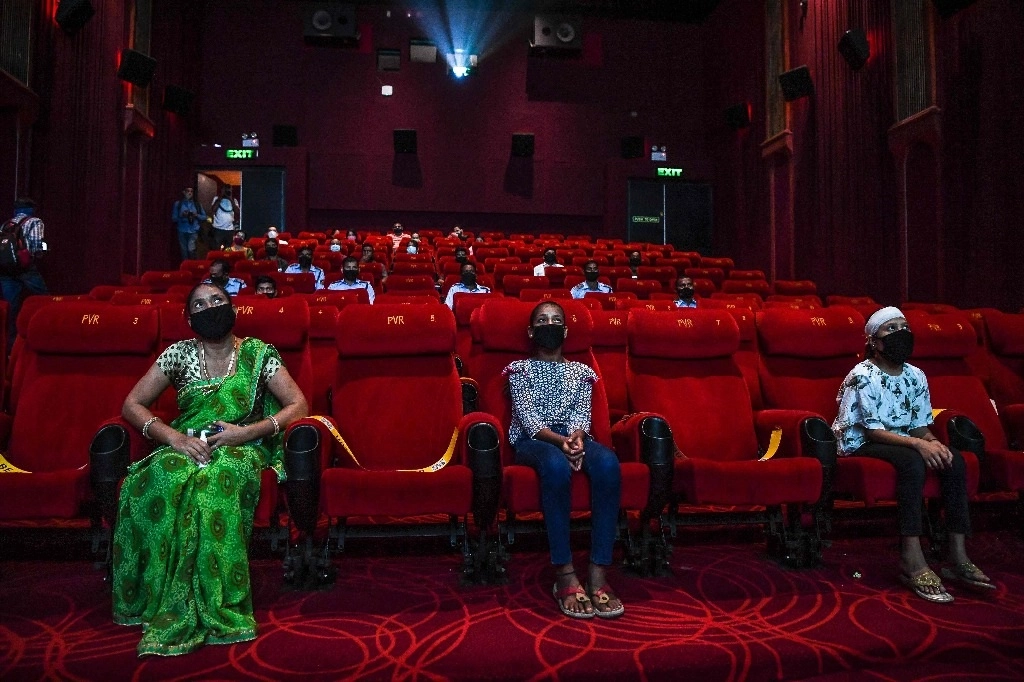 Los cines de algunas partes de India reabrieron este jueves luego de ocho meses. El personal de los cines recibió con flores a los primeros asistentes. Foto Afp