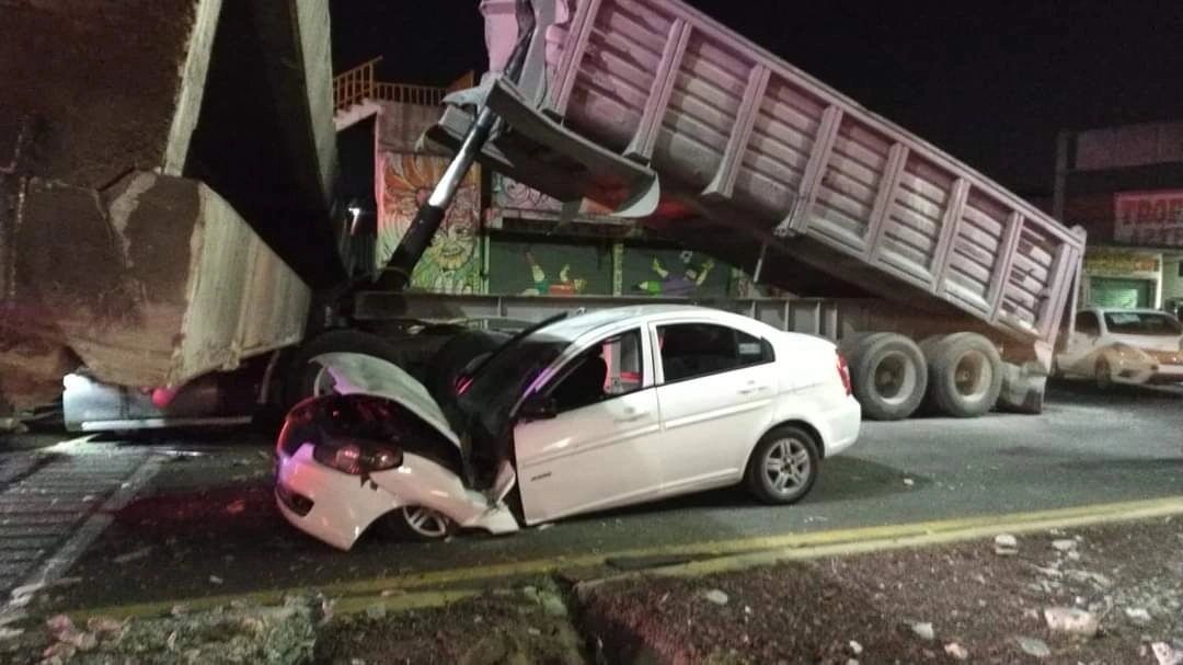 Un vehículo fue aplastado y su conductor resultó lesionado luego de que ayer, en el kilómetro 30 de la carretera federal Los Reyes-Texcoco, un tractocamión que presuntamente excedía las dimensiones reglamentadas de carga derribó un puente peatonal. Foto ‘La Jornada’