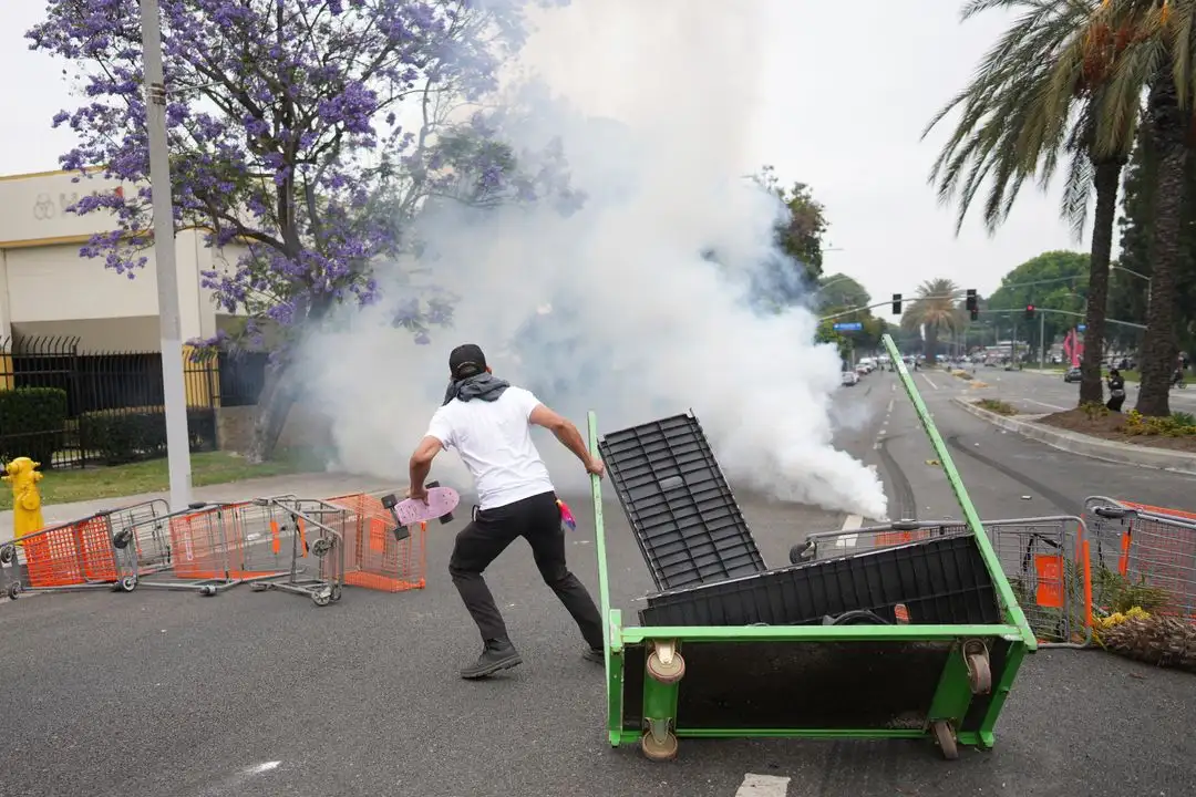 Un manifestante observa mientras personal de la Patrulla Fronteriza con equipo antidisturbios y máscaras de gas monta guardia afuera de un parque industrial en la ciudad de Paramount, California, el 7 de junio de 2025. Foto 