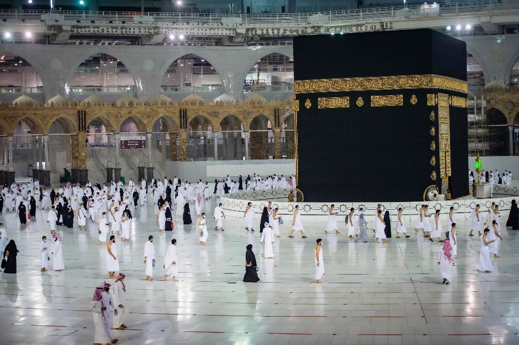 Los musulmanes practican el distanciamiento social mientras rezan alrededor de la Kaaba, el edificio cúbico de la Gran Mezquita durante el primer día en que se permitió reiniciar las peregrinaciones de la umrah. Foto Ap
