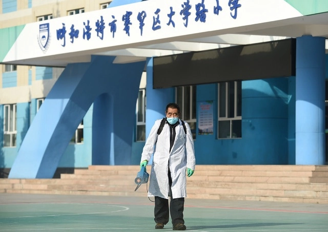 Una persona realiza trabajos de desinfección en una escuela ubicada en Hohhot, China. Foto Xinhua