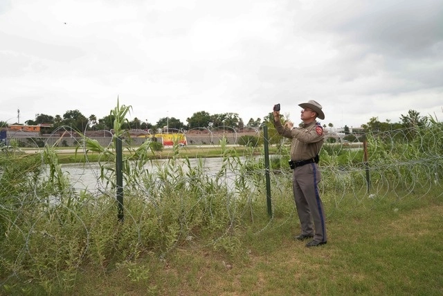 Un policía estatal toma una foto mientras el gobernador de Texas, Greg Abbott, recorre la frontera entre EU y México en el río Grande en Eagle Pass el pasado 23 de mayo de 2022. Foto Afp