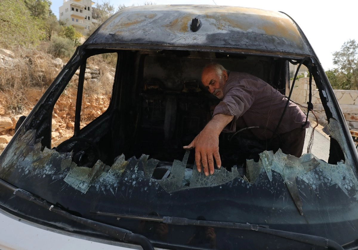 Un palestino observa los restos de su vehículo después de ser incendiado por colonos israelíes en Far'ata, Cisjordania, el 2 de noviembre de 2025. Foto 