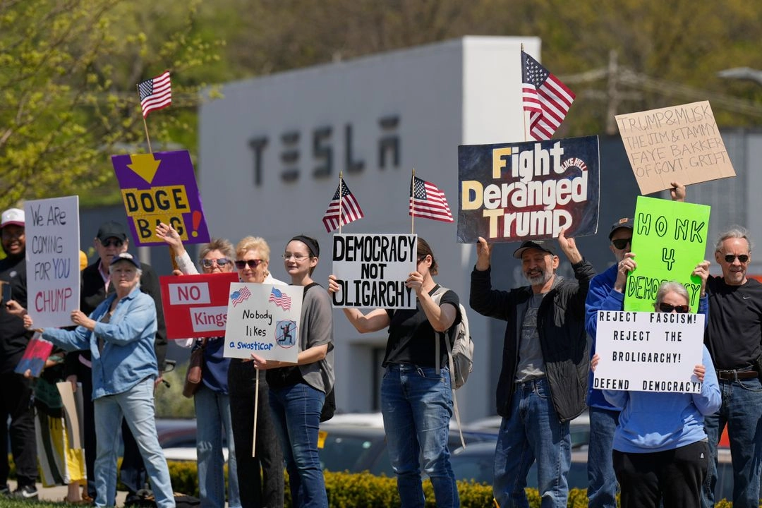 Manifestantes protestan contra los recortes de eficiencia de Elon Musk y el Departamento de Gobierno frente a un concesionario de Tesla en Kansas City, el 12 de abril de 2025. Foto 