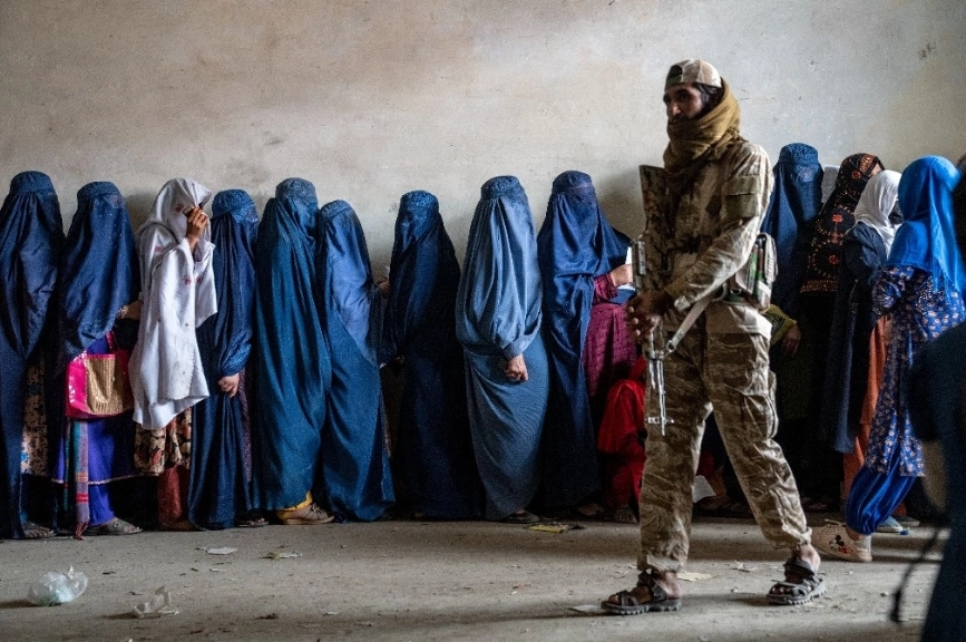 Un combatiente talibán vigila a las mujeres que esperan recibir raciones de alimentos distribuidas por un grupo de ayuda humanitaria, en Kabul, Afganistán.