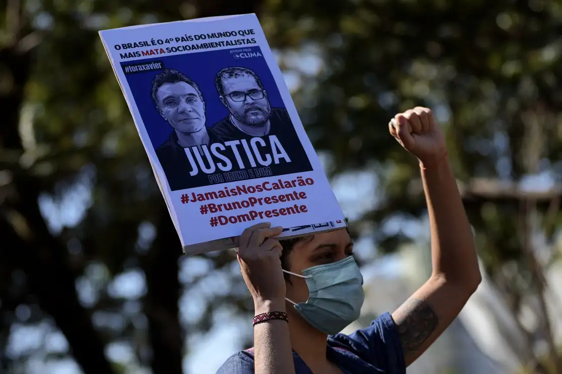 Un activista sostiene un cartel con imágenes del periodista británico Dom Phillips, a la izquierda, y el experto indígena Bruno Pereira, en el que se lee la palabra "Justicia" escrita en portugués, durante una manifestación para exigir a las autoridades que realicen una investigación exhaustiva sobre las circunstancias que llevaron a sus muertes y hagan más para proteger tierras indígenas contra mineros, madereros y pescadores ilegales, en Brasilia, Brasil, el 19 de junio de 2022. Foto Ap