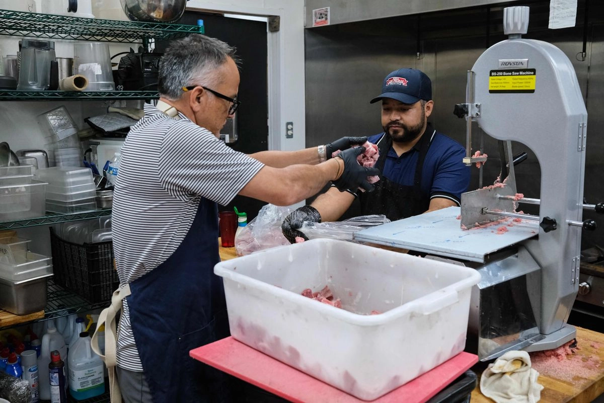 Oscar García Santaella (izq.), propietario del restaurante mexicano Los Primos, recibe la ayuda de uno de sus empleados para preparar comidas en Houston, el 10 de septiembre de 2025.