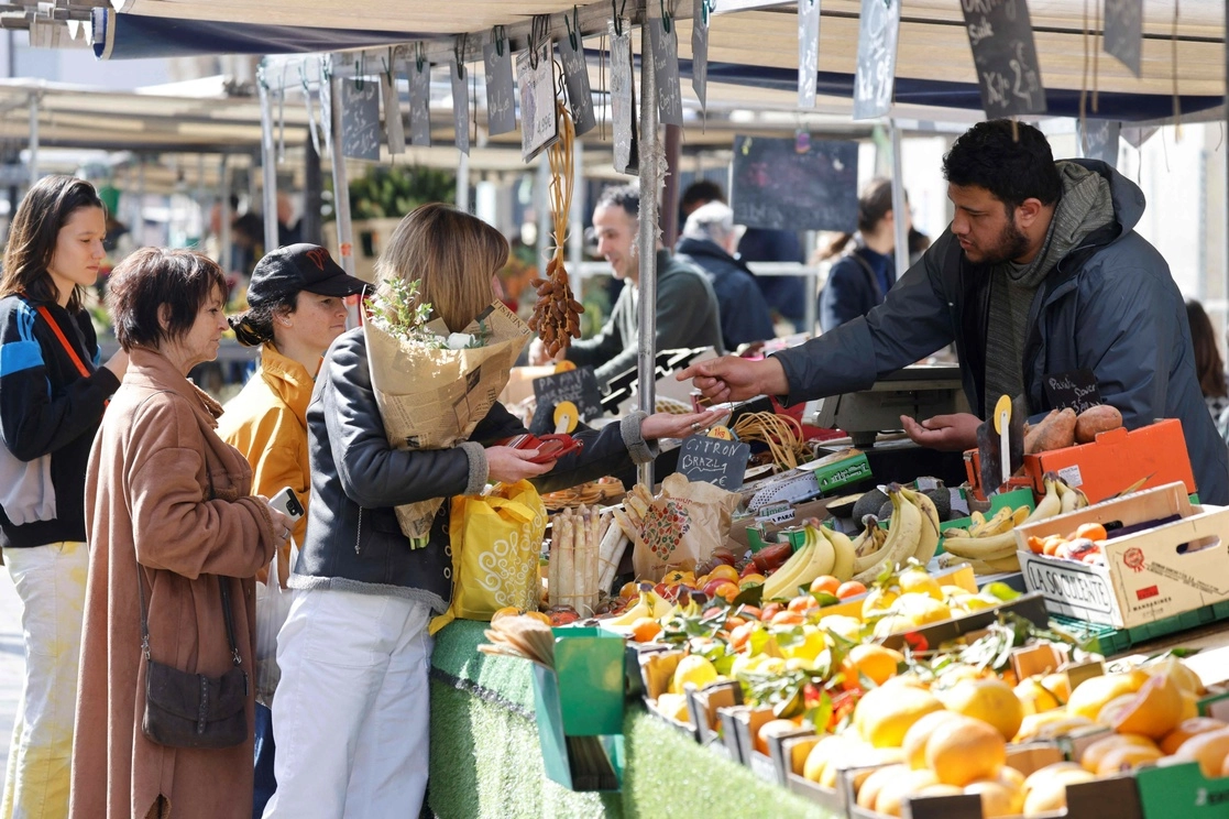 Personas visitan y realizan compras en un mercado al aire libre en París, Francia. Foto Afp