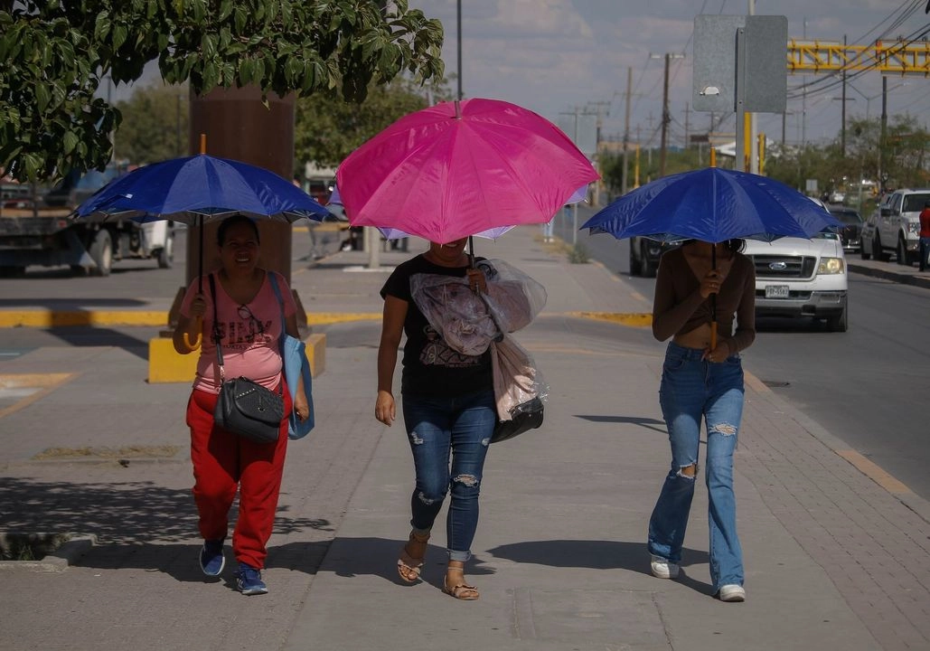 Personas se cubren con paraguas de los rayos directos del sol en Chihuahua. Imagen de archivo. Foto