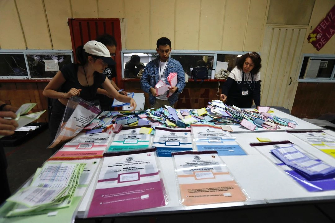 Funcionarios de casilla realizan la separeción de boletas electorales tras el cierre de casillas. Foto 