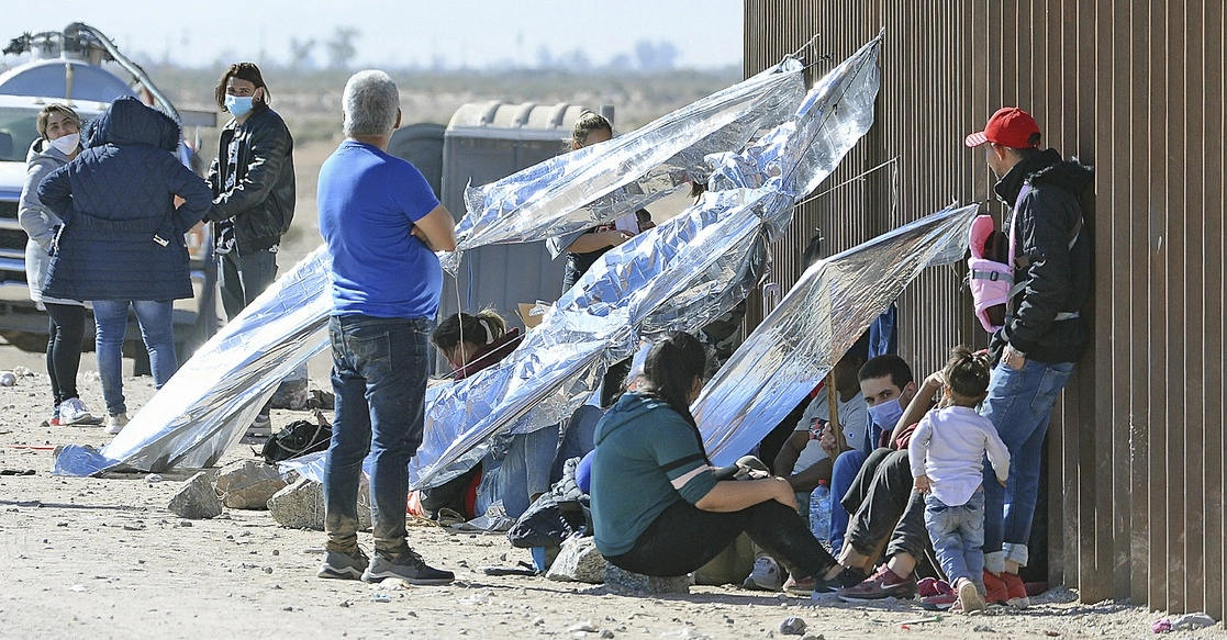 Migrantes que ingresaron a los Estados Unidos cruzando el río Colorado desde México, esperan asistencia en un pequeño campamento improvisado que consta de estructuras hechas con mantas térmicas unidas a un muro fronterizo en el valle de Yuma, Arizona, el 6 de diciembre de 2021. Foto Ap