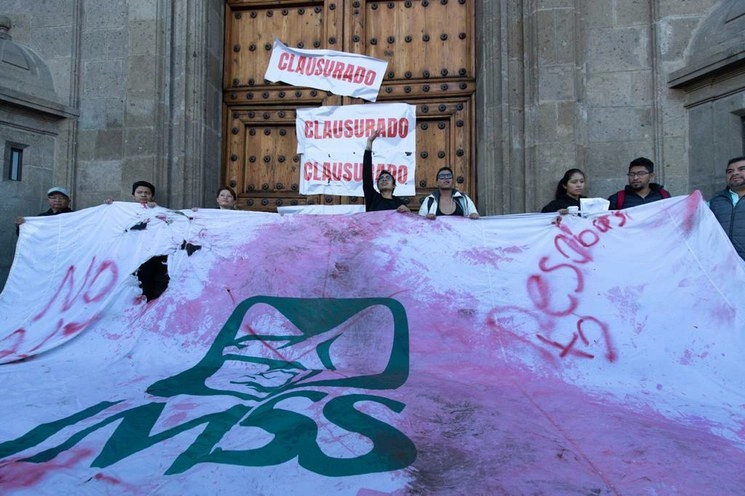 Manifestantes realizan una clausura simbólica del Palacio Nacional, mientras al interior se desarrolla la conferencia matutina del presidente Andrés Manuel López Obrador y el secretario de Salud, Jorge Alcocer. Foto Pablo Ramos