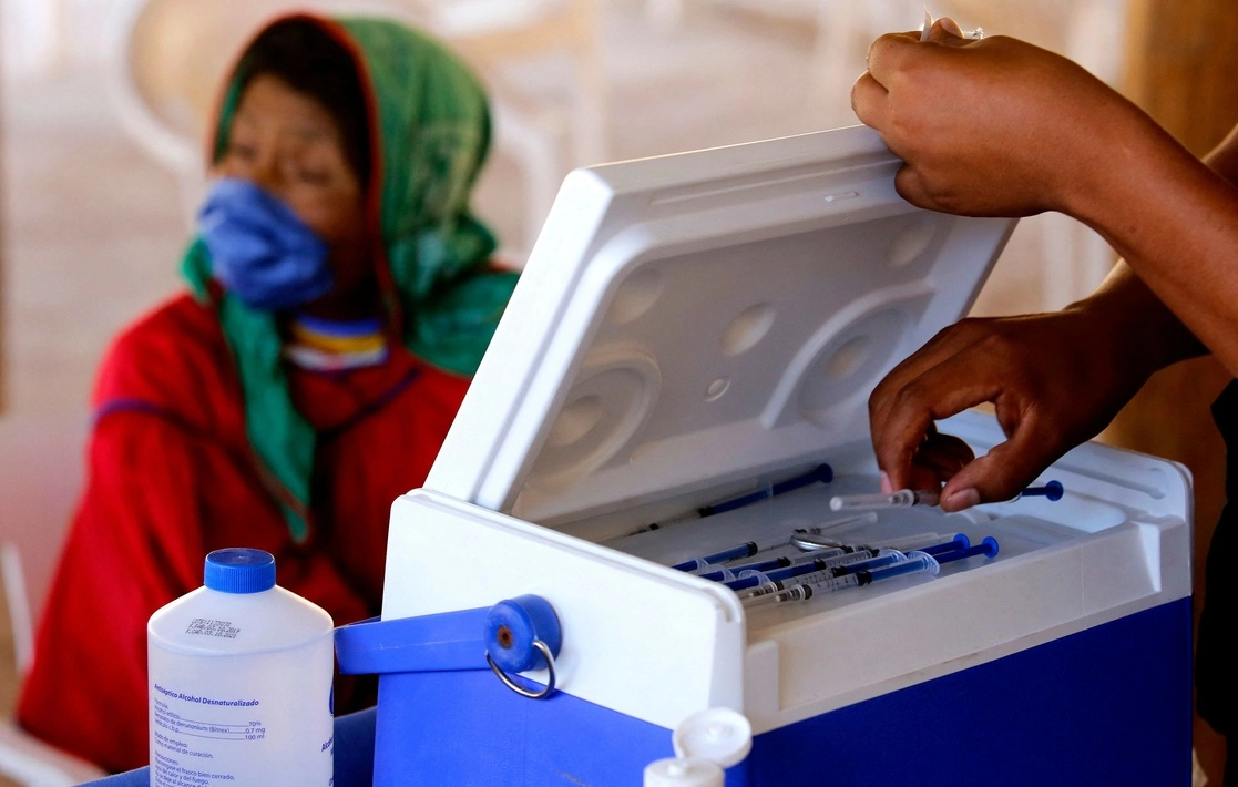 Una enfermera sostiene una jeringa con una dosis de la vacuna Covid-19, de CanSino Biologics, mientras wixarica esperan ser inoculados, en el centro de vacunación instalado en la localidad de Nuevo Colonia, en Mezquitic, Jalisco. Foto AFP 