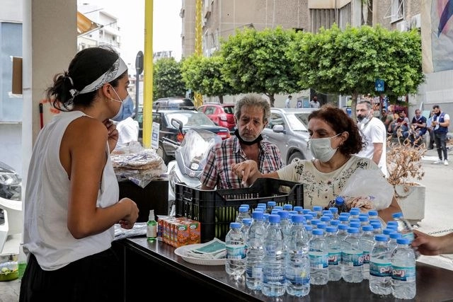 Voluntarios con cubrebocas distribuyen alimentos entre los afectados por las explosiones en Beirut. Foto Afp