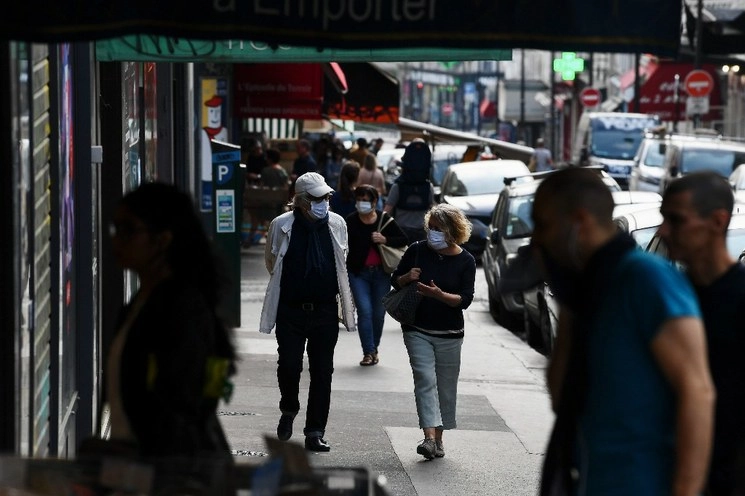 Personas caminan en una calle de París en el día 40 de un estricto encierro destinado a frenar la propagación de la pandemia Covid-19. Foto Afp