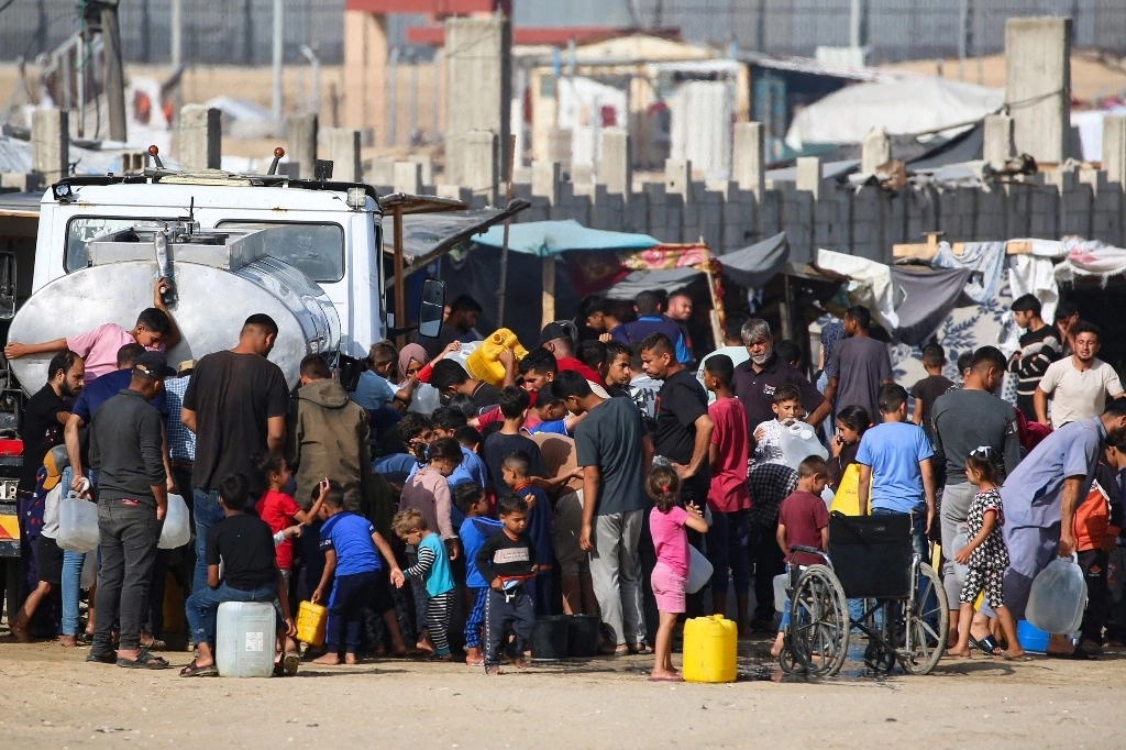 Palestinos desplazados hacen fila para obtener agua en un campamento en Rafah, el 17 de mayo de 2024. Foto Afp