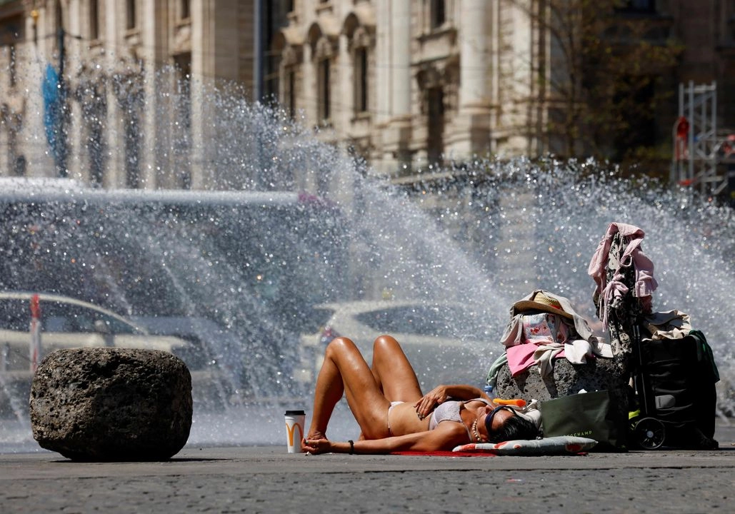 Una mujer se baña al sol junto a una fuente en la plaza Karlsplatz de Múnich, el 29 de junio de 2025, sur de Alemania.  Foto 