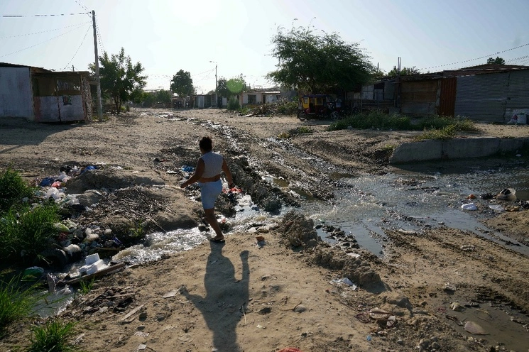 Una mujer cruza una zanja de drenaje en el barrio marginal Los Polvorines en Piura, Perú, el sábado 3 de junio de 2023. Foto Ap