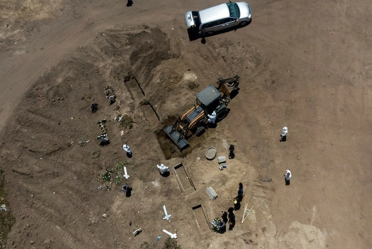 Vista aérea de la inhumación de una víctima de Covid-19, cuyo féretro es manipulado con una máquina. Foto Afp