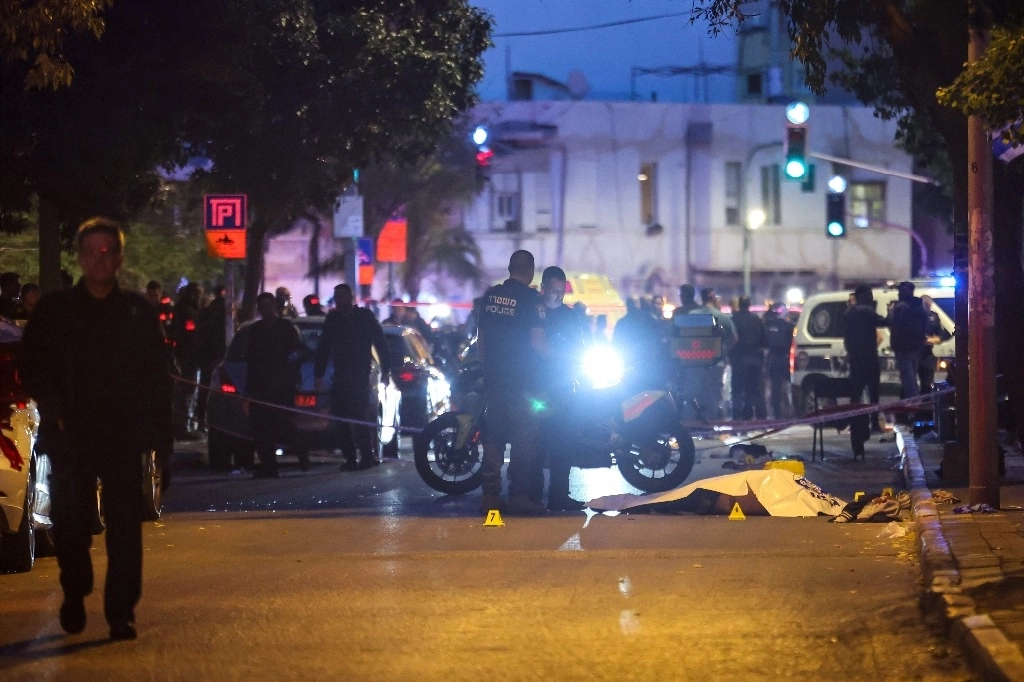 La policía israelí se encuentra junto al cuerpo amortajado del presunto agresor en el lugar de un tiroteo en Tel Aviv el 18 de enero de 2025, un día antes de que entre en vigor un alto el fuego en Gaza tras la aprobación por parte del gabinete israelí de un acuerdo entre Israel y Hamás. Foto Afp
