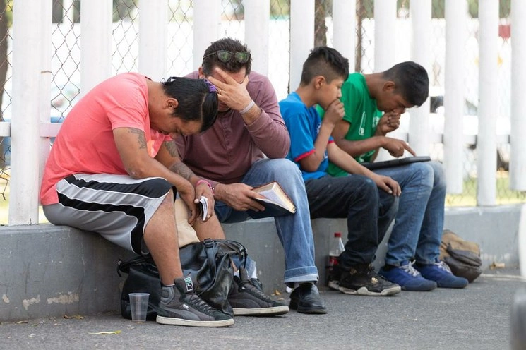 Ciudadanos esperan noticias de familiares internados en el hospital Juan Ramón de la Fuente mientras leen la Biblia y rezan, en la alcaldía de Iztapalapa, Ciudad de México. Foto Pablo Ramos