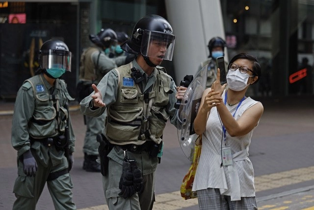 La policía antidisturbios de Hong Kong empuja a una mujer que hablaba con uno de los manifestantes detenidos en Mongkok. Foto Ap