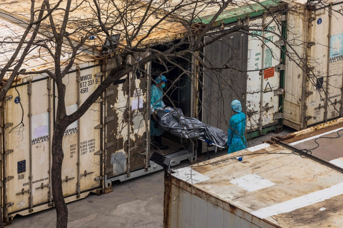 Trabajadores trasladan el cuerpo de una persona fallecida de un camión a un contenedor refrigerado en el depósito de cadáveres público de Fu Shan en Hong Kong, en medio del peor brote de covid-19 de la historia de la ciudad, el 16 de marzo de 2022. Foto Afp
