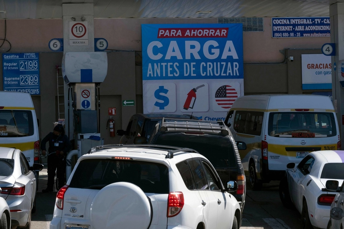 Un letrero en una estación de servicio en Tijuana aconseja a los automovilistas llenar sus tanques de gasolina antes de cruzar a Estados Unidos y ahorrar dinero. Foto Afp