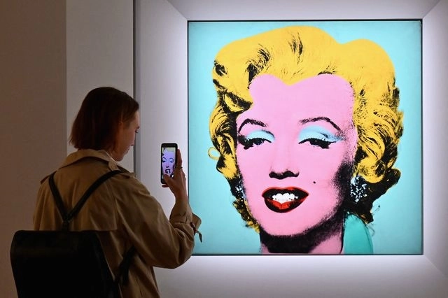 Una mujer toma una foto del retrato 'Shot Sage Blue Marilyn' de Andy Warhol. Foto Afp 