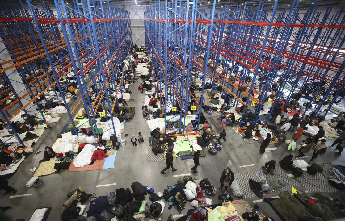 Migrantes se resguardan del mal clima en un centro logístico en Bielorrusia. Foto Ap