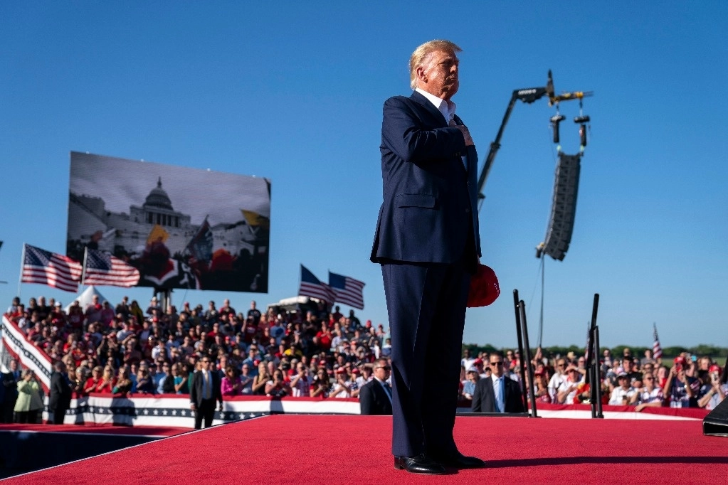 Donald Trump, con la mano en el corazón, durante el acto político en Texas donde rindió homenaje a los participantes en el intento de golpe de Estado durante el asalto al Capitolio el 6 de enero de 2021. Al fondo, las pantallas muestran imágenes del intento por tomar el Congreso estadunidense. Foto Ap.